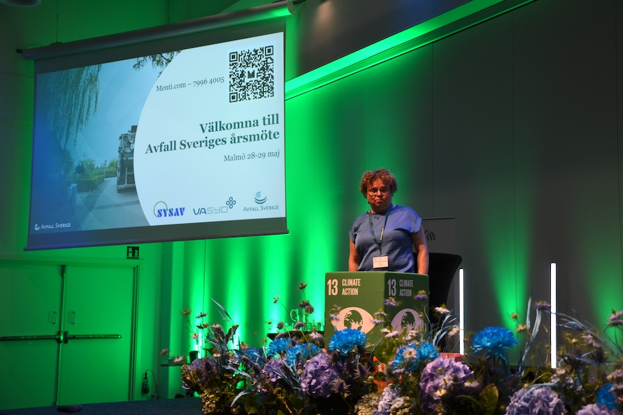 Maria Wolrath Söderberg föreläser på Avfall Sveriges årsmöte, med blommor och kuber som visar FNs globala mål på scenen.